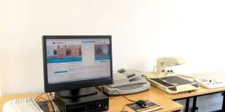 an accessible computer sits on a desk with a scanner and other assistive technology