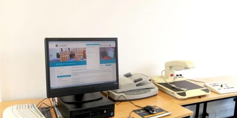 an accessible computer sits on a desk with a scanner and other assistive technology