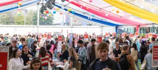 People crowded in a tent around stalls