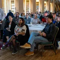 a wide shot of everyone in attendance sitting at tables looking to the front of the room 