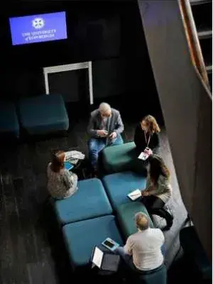 An almost aerial view of a group of five people sitting together and talking. 