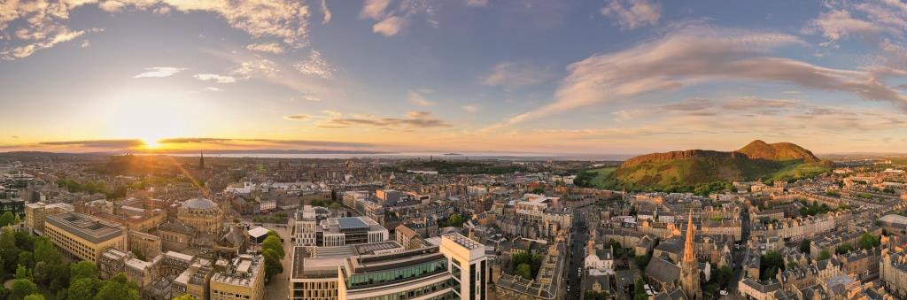 Drone image of George Square buildings, the city, Arthur's Seat and the Firth of Forth in the background.