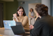 Image of 2 people smiling and having a discussion in an office