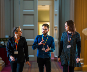 Three university staff walk down a corridor with the centre person explaining something