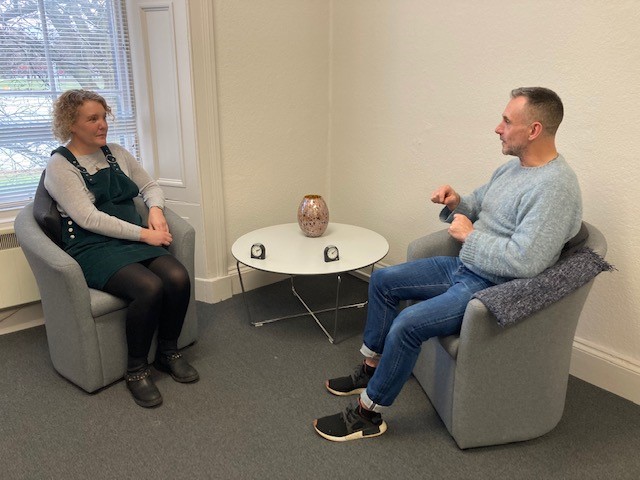 man and woman talking in armchairs