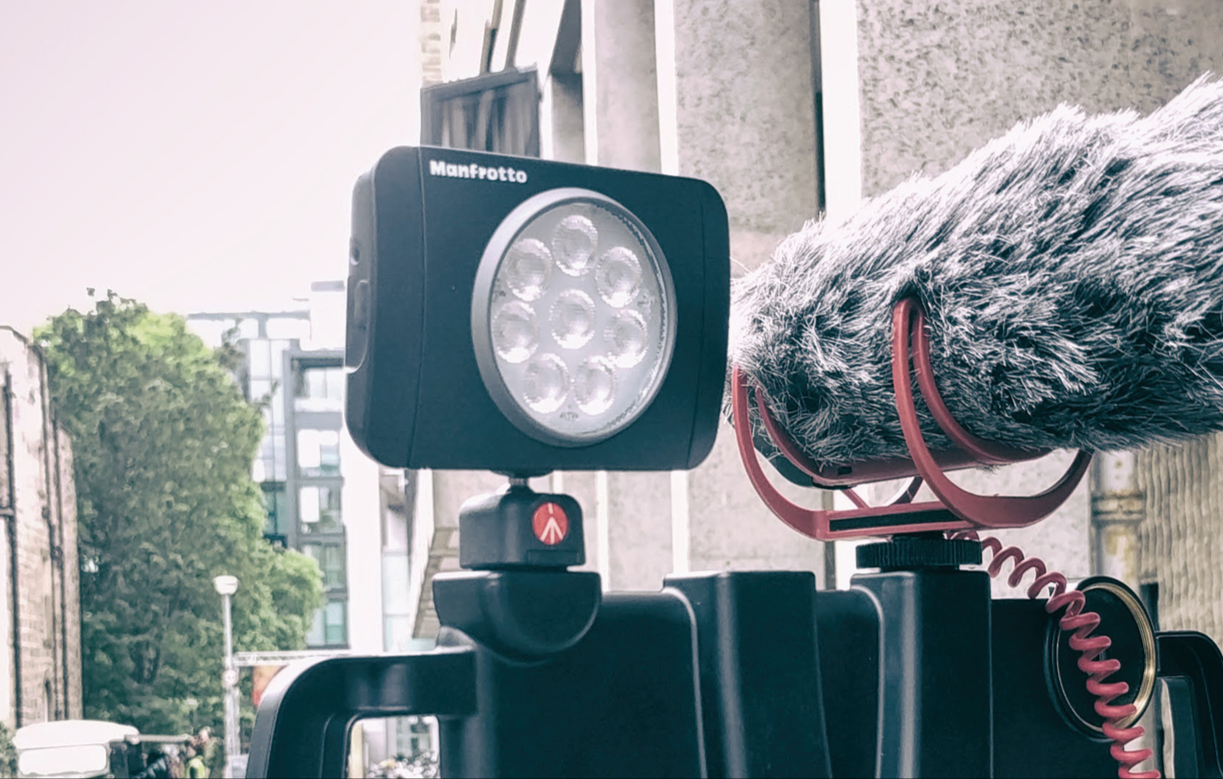 An outboard light is shown mounted on top of a mobile phone filming rig.