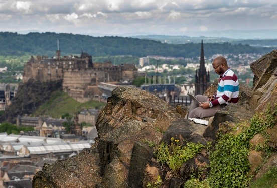 Man on laptop on hillside 